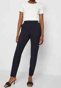 Námořnické kalhoty na míru s hladkou texturou, slim fit a jemnými pruhy; doplněné o přiléhavé bílé tričko s krátkým rukávem.