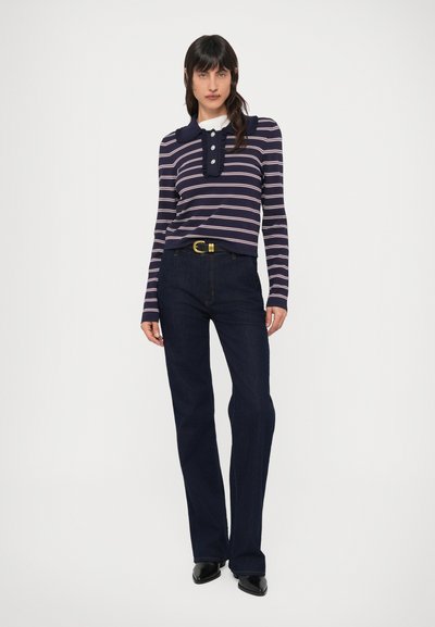 Μπλούζα μακρυμάνικη με ναυτικό και λευκό ριγέ μοτίβο, γιακά και κουμπιά, συνδυασμένη με σκούρο μπλε τζιν παντελόνι με ίσια γραμμή και μαύρα παπούτσια.