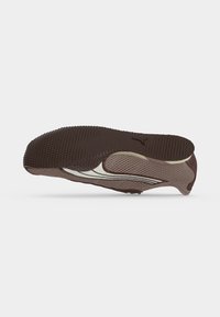 Chaussure de sport marron clair avec semelle texturée marron foncé et logo Puma blanc sur le côté, vue d'un angle inférieur.