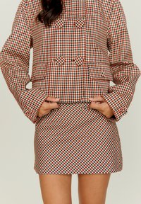 Κόκκινο και λευκό καρό κομμένο μπουφάν με ταιριαστή μίνι φούστα, με σχέδιο διπλού κούμπωματος και κουμπιά για διακοσμητικά στοιχεία.