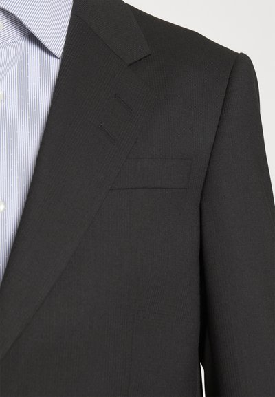 Fekete zakó, textúrált anyagból készült, egysoros kialakítással, éles hajtókákkal és egy mellzsebbel. Alatta egy csíkos kék ing látható.