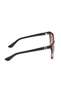 Lunettes de soleil avec une monture noire et des verres foncés, dotées d'une finition brillante, d'accents dorés et d'une forme rectangulaire en œil de chat.