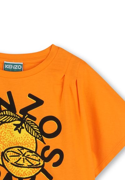 T-shirt en coton orange avec un graphique noir d'une orange coupée en deux et des feuilles, avec "KENZO" imprimé en lettres majuscules. Manches courtes.