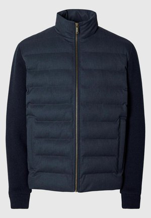 Navy puffer jacket with a high collar, featuring a quilted front, knitted sleeves, and a gold zipper. Smooth texture with a modern design.