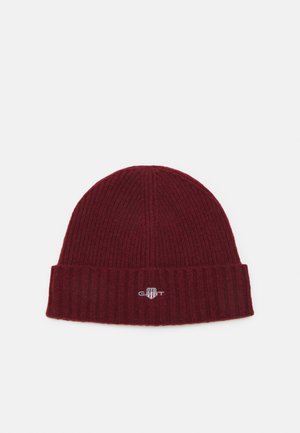 Burgundy knit beanie with a ribbed texture and a folded brim. Features a small, embroidered logo on the front. Soft material.