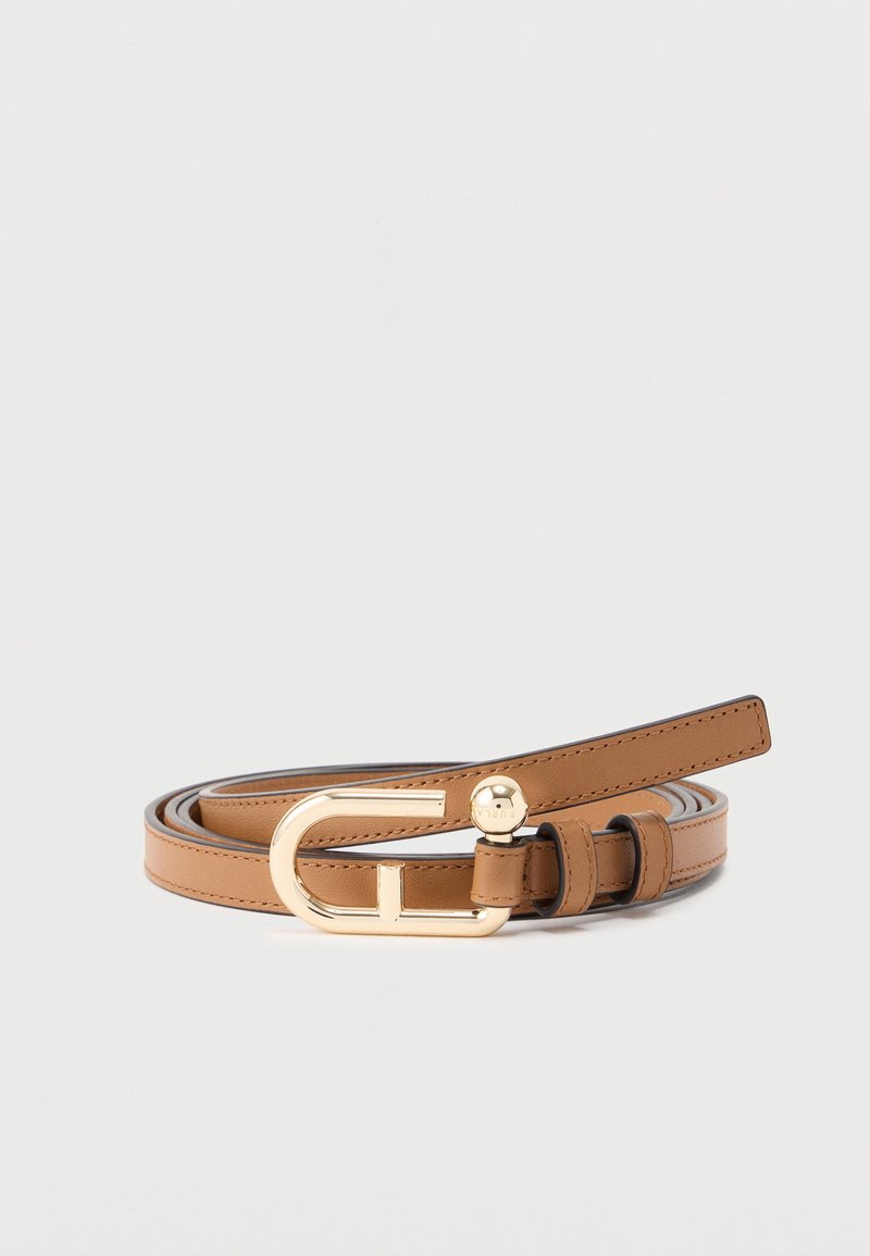 Λεπτή ταμπά δερμάτινη ζώνη με χρυσή οβάλ αγκράφα και μικρή χρυσή λεπτομέρεια με καρφί, τυλιγμένη σε απλό ανοιχτό γκρι φόντο.