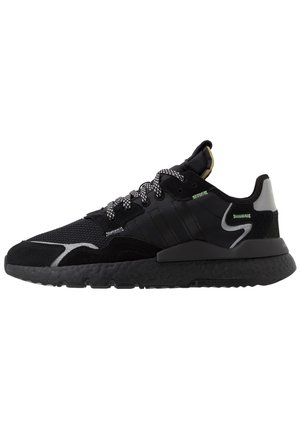 Zwarte sportschoenen met een bovenwerk van mesh en suede, een gestructureerde rubberen zool, vetersluiting en reflecterende accenten aan de zijkanten.