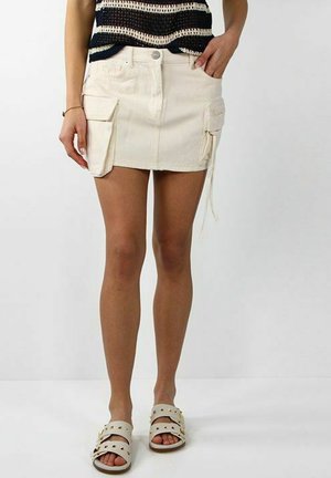 Gonna mini in denim bianco con tasche cargo, caratterizzata da una chiusura con bottone e zip. Orlo arrotondato e superficie leggermente testurizzata.
