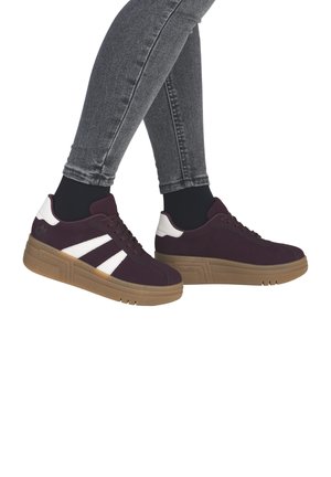 Legs wearing fitted grey jeans and black socks with dark purple sneakers featuring white accents and tan soles.