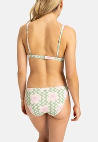 Bikini set v zelenej farbe s kvetinovým vzorom, ktorý obsahuje ružové kvety a štruktúrovaný dizajn. Nastaviteľné ramienka a zapínanie na klip na zadnej strane.