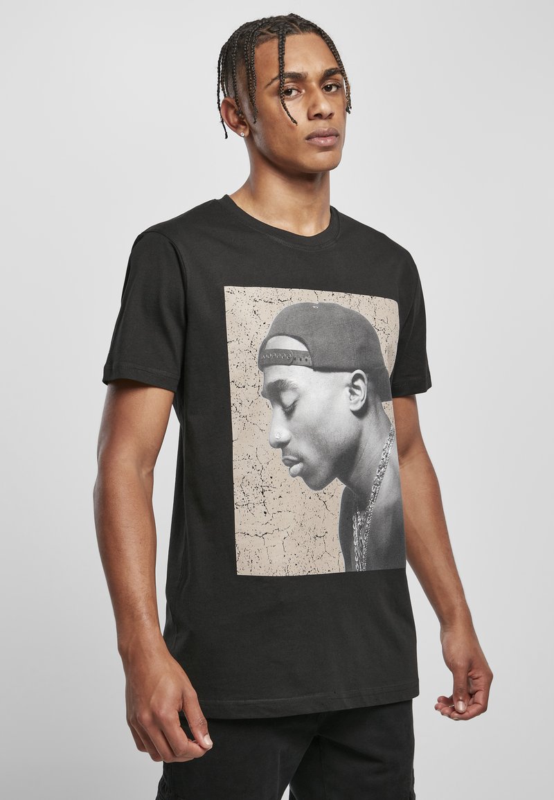 Schwarzes Baumwoll-T-Shirt mit einem großen, vintage-inspirierten Grafik eines Personenprofils auf einem beigen, rissigen Hintergrund. Kurze Ärmel, Rundhalsausschnitt.