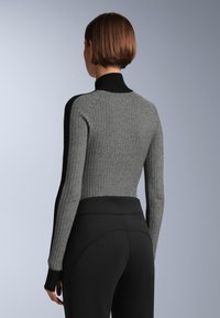 Prilagođeni pulover sa crno-bijelim uzorkom, visokog ovratnika i dugim rukavima. Rebrasti manžeti i rub, teksturirana pletenina.