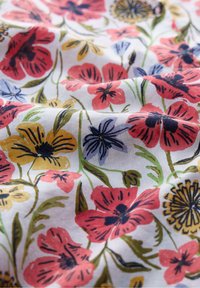 Tessuto floreale con fiori vivaci di colore rosa, giallo e blu su uno sfondo bianco. Presenta dettagli intricati e accenti di foglie verdi.