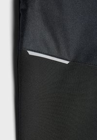 Pantaloni sportivi neri realizzati in tessuto morbido, con un pannello superiore texturizzato nero e un accento riflettente argentato lungo la cucitura.