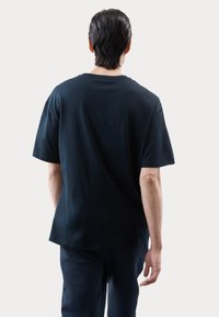 T-shirt nera a maniche corte in cotone, con una vestibilità comoda e colletto tondo. Tessuto liscio, senza motivi o grafiche visibili.