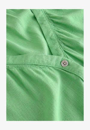 Roheline kangasest särk, millel on tekstuuriga viimistle, nuppudega detail ja kokku gatherd õmblus kaelaosa ääres. Pehme, kerge materjal.