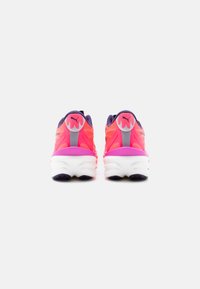 Ζευγάρι ροζ και μοβ παπούτσια τρεξίματος Puma, που φαίνονται από πίσω, εμφανίζοντας το λογότυπο φλόγας στη φτέρνα και άσπρες επενδυμένες σόλες σε απλό φόντο.