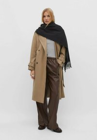 Beige trenchcoat, sort tørklæde, stribet bluse, brune faux læderbukser, vide ben, lange ærmer, dobbeltradet, blød tekstur, afslappet design.