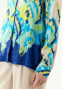 Lange mouwen blouse van lichte stof, met een levendig blauw en groen abstract patroon, voorzien van een knoopmanchet en een relaxte pasvorm.
