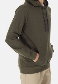 Olijfgroene hoodie met een voorzak, capuchon met trekkoord, ribgebreide manchetten en onderrand. Het materiaal is zacht, met een gladde textuur en gestikte logo-details.