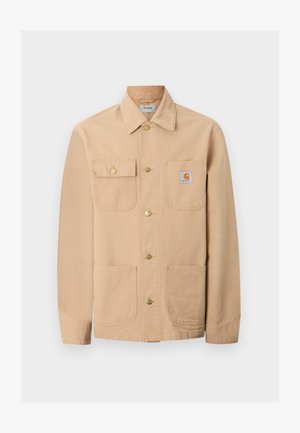 Μπεζ μπουφάν Carhartt με τέσσερις μπροστινές τσέπες, κούμπωμα με κουμπιά και ετικέτα με το λογότυπο της μάρκας στην δεξιά τσέπη στο στήθος.
