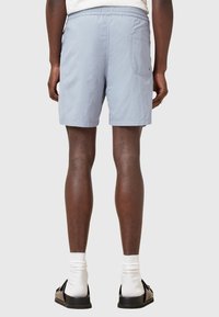 Pantaloni corti azzurri chiari realizzati in tessuto tessuto, con vita elastica, tasca laterale e lunghezza sopra il ginocchio. Design minimalista.