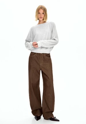 Light gray cropped sweater with wide sleeves and a round neckline, paired with high-waisted, dark brown wide-leg jeans. Textured fabric.