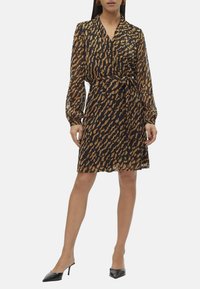Robe portefeuille à motifs noirs et bruns, avec des manches longues, une ceinture à nouer et une silhouette fluide, fabriquée à partir d'un matériau léger et transparent.