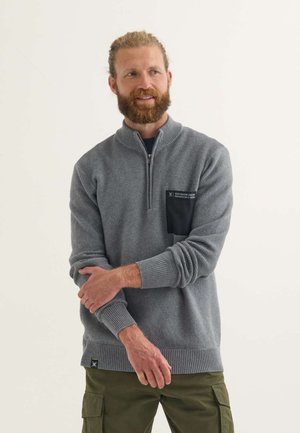 Grauer Strickpullover mit Reißverschlusskragen, strukturiertem Stoff, Rippbündchen und -saum sowie einer schwarzen Brusttasche mit weißem Textetikett.