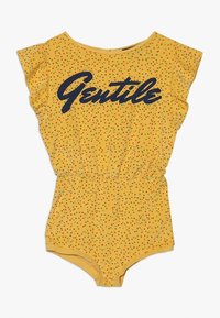 Mono amarillo con mangas cortas aladas, cintura elástica y un patrón de lunares en rojo y verde. Presenta la palabra "Gentile" impresa en azul oscuro.