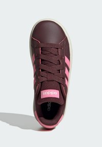 Zapatillas sintéticas marrones con acentos rosas. Presentan puntera redondeada, lengüeta de malla, tres rayas rosas y etiqueta de marca en la lengüeta.