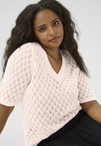 Light pink short-sleeve knit sweater with a V-neck, featuring a lace pattern and ribbed edges. Soft texture and loose fit.