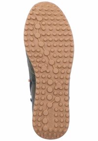 Semelle en caoutchouc marron avec des motifs circulaires en relief et une surface texturée, comportant un logo. Conçue pour l'adhérence et la durabilité.