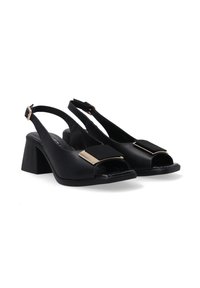 Escarpins slingback noirs en cuir synthétique. Dotés d'une large bride avec un accent doré et d'un talon bloc. Design à bout ouvert.