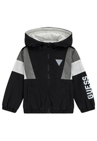 Giacca a vento nera e grigia con cappuccio, chiusura a zip, polsini elastici e un logo bianco sulla manica. Presenta un design a blocchi di colore.