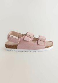 Roze suède sandaal met twee verstelbare riemen, een zachte inlegzool en een witte rubberen zool. Heeft een lichte hak en een gestructureerd oppervlak.