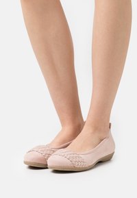 Jasnoróżowe płaskie buty wykonane z zamszu, z tkaną teksturą na palcach, o zaokrąglonym kształcie i elastycznej gumowej podeszwie.