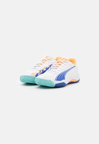 Baskets de sport blanches avec des accents bleus et des détails orange. Présentent des semelles texturées et une surface lisse. Conçues pour la performance et le confort.