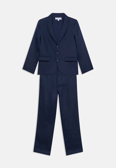 Costum formal bleumarin cu sacou cu trei nasturi și buzunare cu clapetă, asortat cu pantaloni drepți de aceeași culoare.