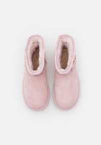 Botines de ante rosa claro, con un suave forro de forro polar y costuras a medida, con una forma de punta ligeramente redondeada.