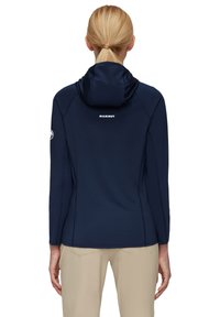 Navyblaue Softshell-Jacke mit Kapuze, die ein Logo auf dem Rücken und flache Nähte aufweist, entworfen für Outdoor-Aktivitäten.