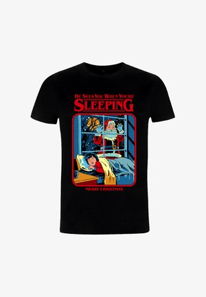 Czarny bawełniany t-shirt z kolorową grafiką Świętego Mikołaja obserwującego śpiącego chłopca, z czerwonym i niebieskim napisem "On widzi, kiedy śpisz".