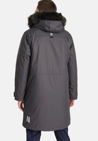 Parka lunga grigia con cappuccio foderato in pelliccia, polsini elasticizzati e dettagli riflettenti vicino all'orlo. Tessuto liscio con un design elegante.