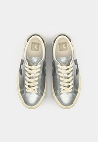 Sneaker con lacci con tomaia in pelle metallizzata argento, suola in gomma crema e accenti neri del logo sui lati; design con punta rotonda.