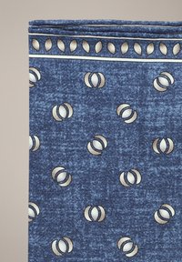 Niebieska tkanina w wzory z małymi złotymi i białymi okrągłymi wzorami. Tekstura wydaje się miękka, o jakości przypominającej dżins.