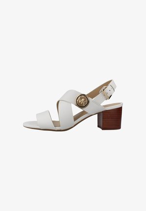 Sandalo in pelle bianca con cinturini incrociati, bottone con logo MK dorato, fibbia regolabile alla caviglia e tacco a blocco in legno.