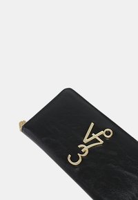 Zwarte leren portemonnee met een gestructureerde afwerking, voorzien van een gouden logo-detail. Rechthoekige vorm met ronde hoeken en gouden hardware accenten.