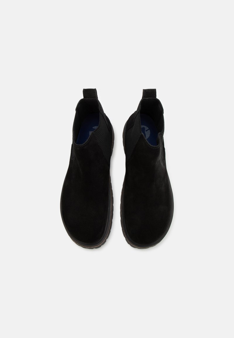 Bottines en suède noir avec des panneaux élastiques sur les côtés, semelles en caoutchouc plates et languettes à l'arrière pour un enfilage facile. Texture lisse et forme arrondie.