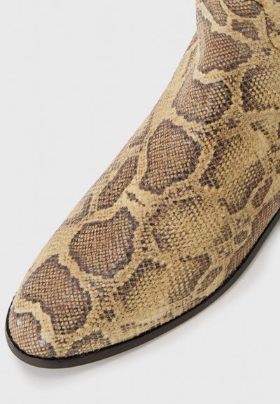 Szpiczasty botek za kostkę w wzór skóry węża, wykonany z beżowo-brązowej teksturowanej powierzchni, z elegancką czarną podeszwą i ozdobnym przeszyciem.