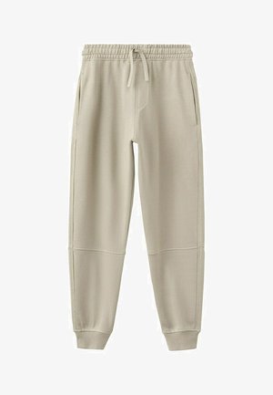 Pantalon de jogging beige avec taille élastique, cordon de serrage, poches latérales, empiècements cousus aux genoux et poignets côtelés aux chevilles.